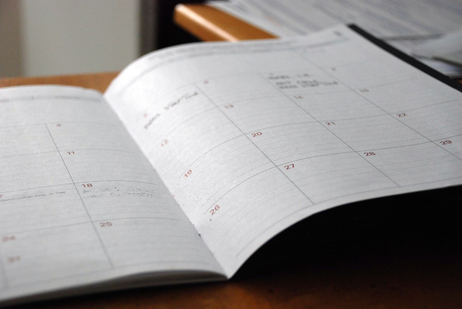 An open monthly planner lying on a wooden desk