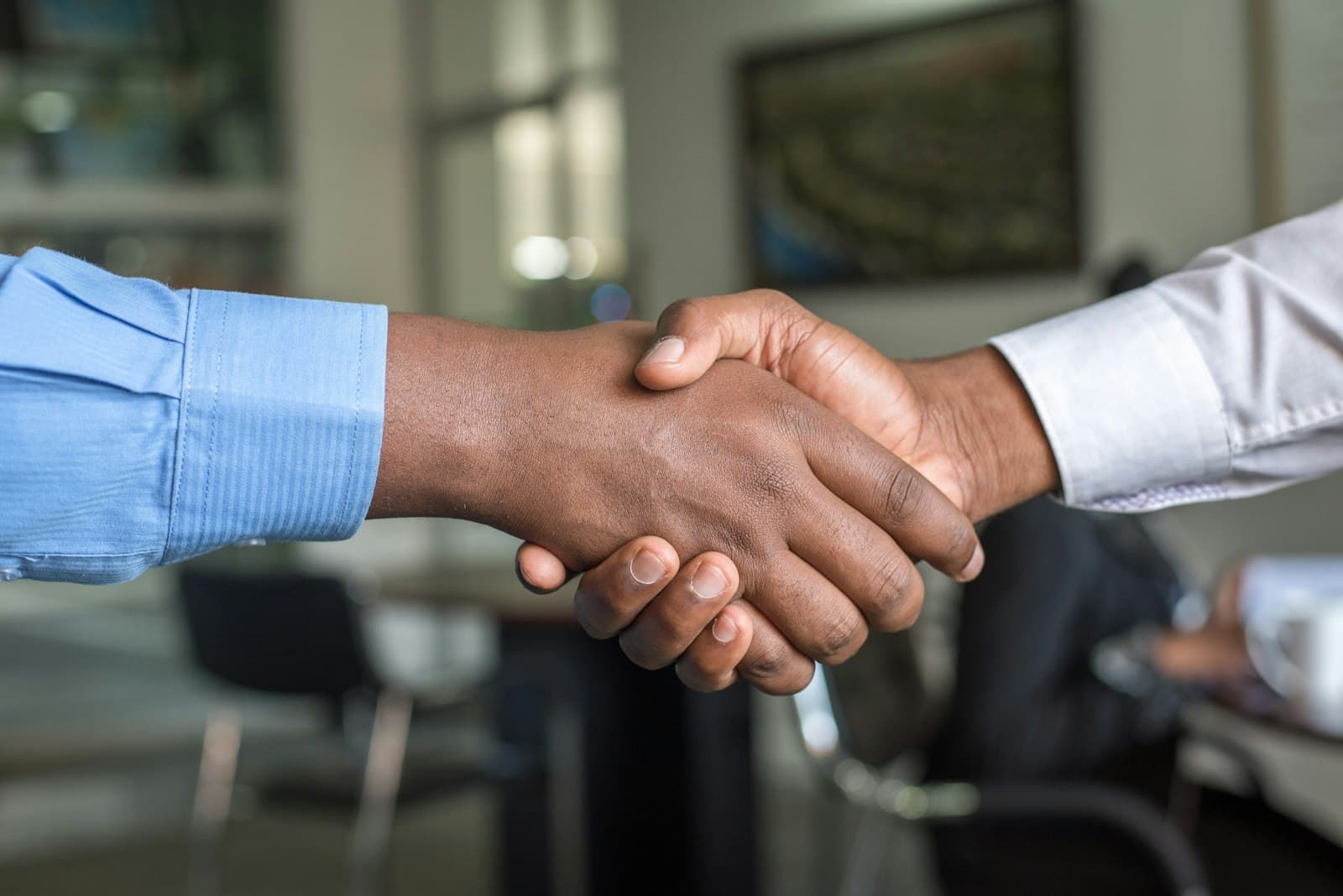 Two people shaking hands in an office meeting room