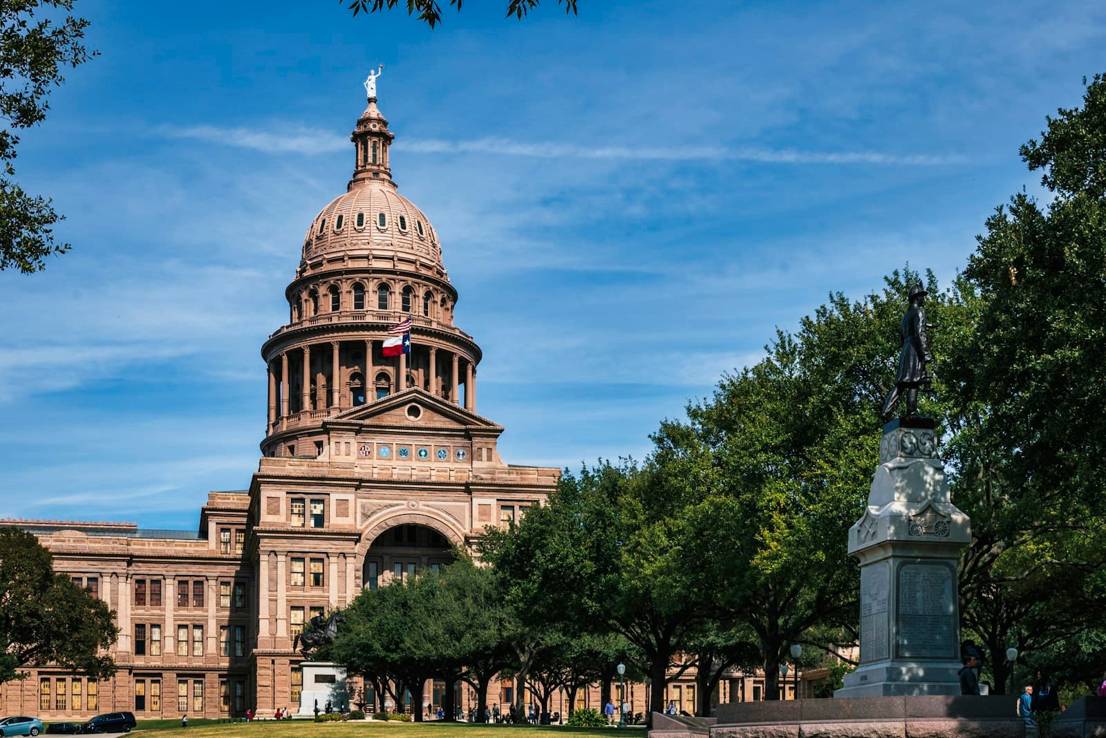 A state capitol building with a dome, framed by trees under a blue sky